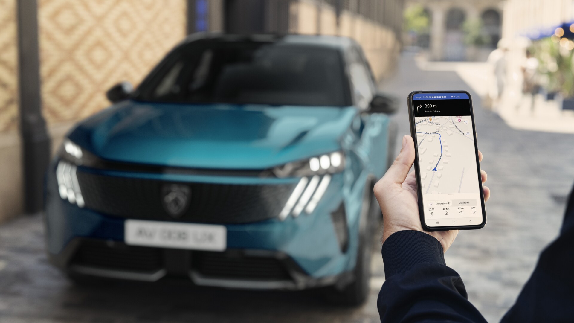 Een man kijkt op zijn smartphone bij de PEUGEOT E-3008